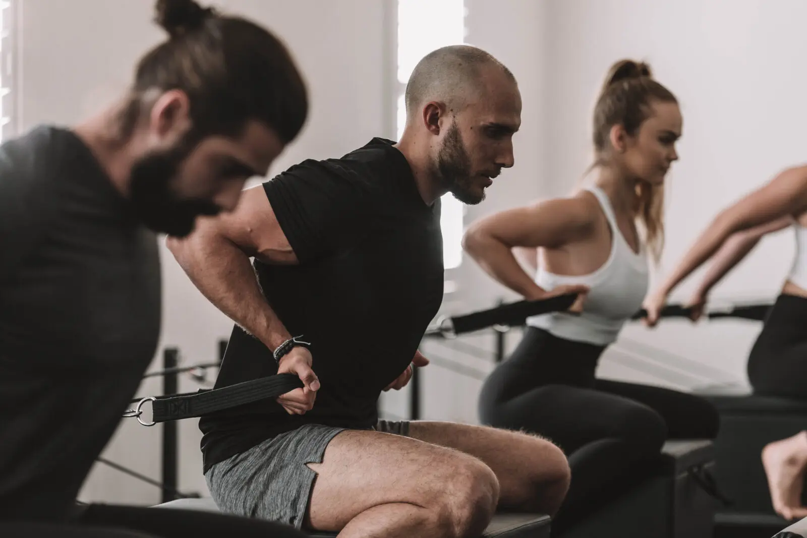 People in a fitness class seated and performing resistance band strength exercises indoors.