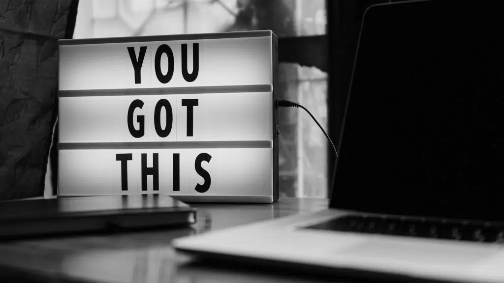 Light box with the message YOU GOT THIS next to a laptop and closed notebooks on a desk