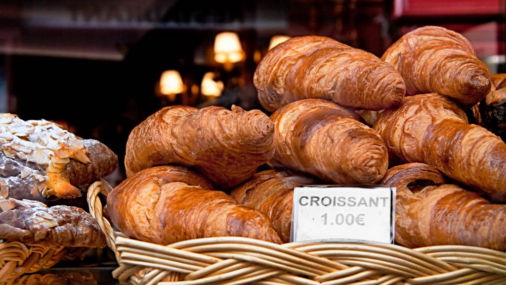 Basket of croissants for sale with a sign showing price of 1.00 euro each.